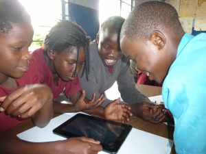 small group of pupils gathered around a tablet computer